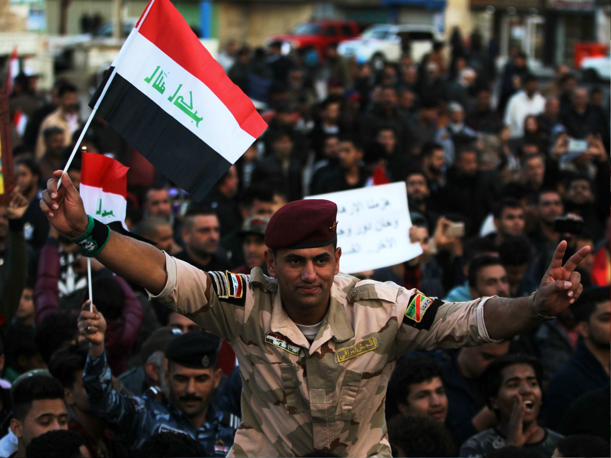 An Iraqi soldier waves his national flag in Baghdad's Tahrir Square on 10 December during a gathering celebrating the end of the three-year war against Isis