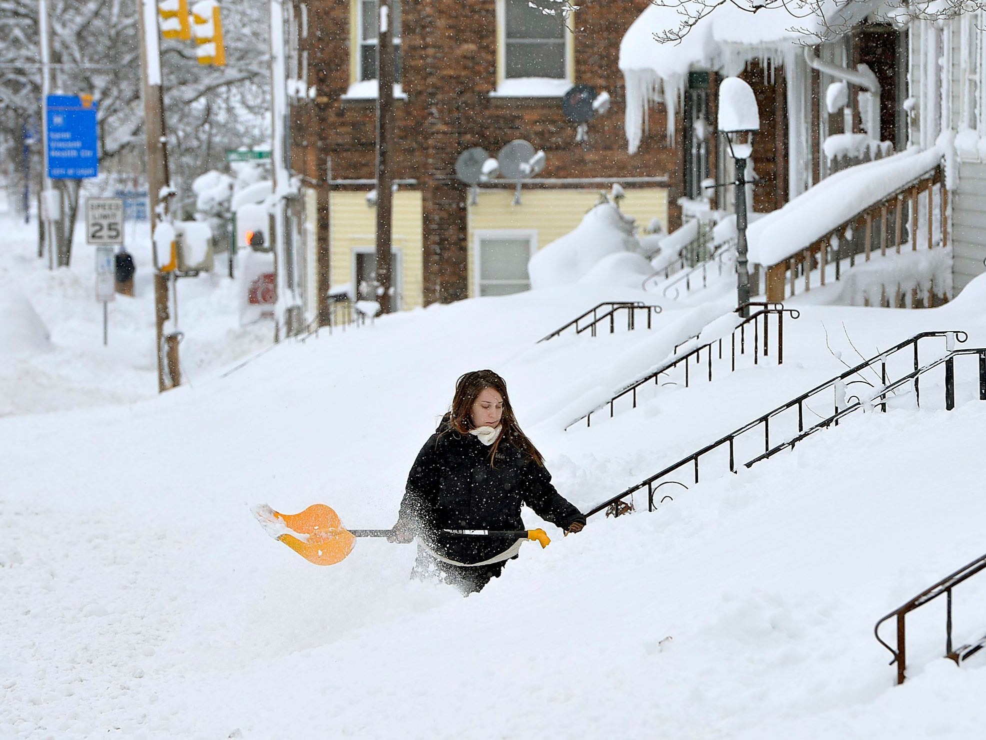 Rochelle Carlotti, 28, shovels steps near her home after a record snowfall in Erie, Pa