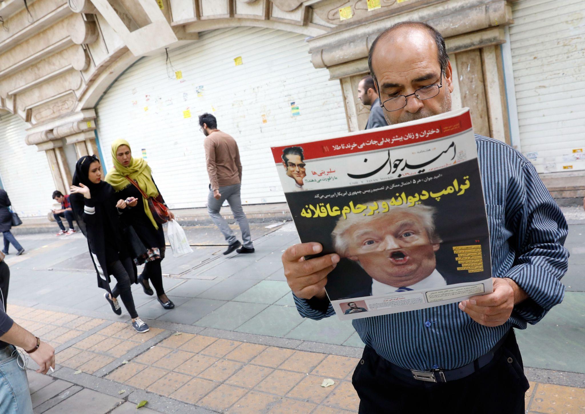 An Iranian man reads a copy of the daily newspaper 'Omid Javan' bearing a picture of US President Donald Trump with a headline that reads in Persian 'Crazy Trump'