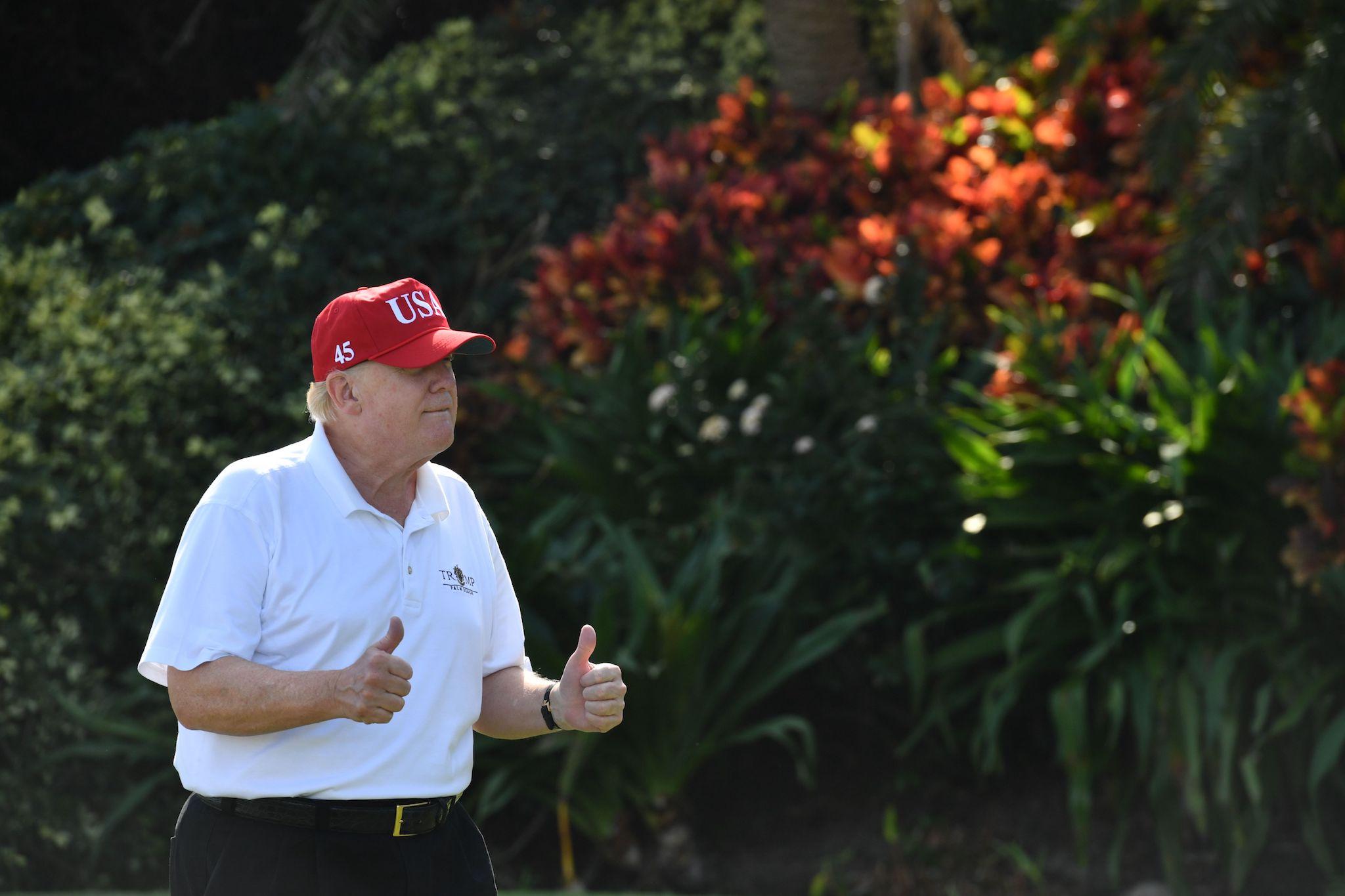 US President Donald Trump holds two thumbs up while meeting with service members of the United States Coast Guard to play golf at Trump International Golf Course in Mar-a-Lago, Florida on December 29, 2017