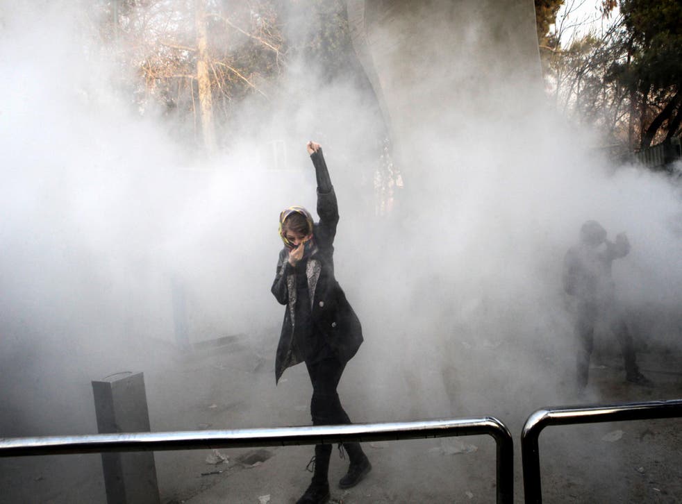 An Iranian woman raises her fist amid the smoke of tear gas at a protest at the University of Tehran