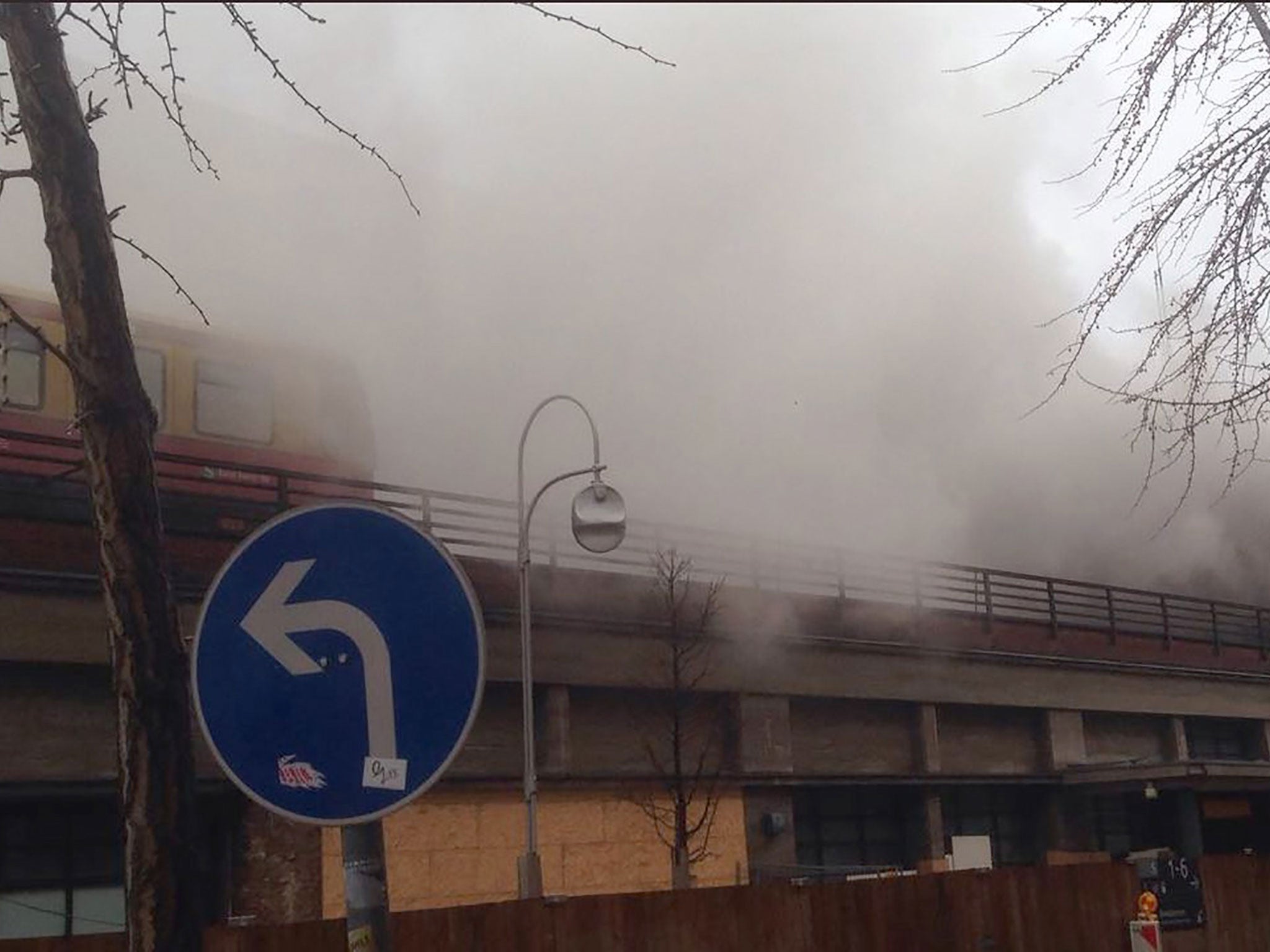 Dense smoke hanging over an S-Bahn suburban train (L) and the Bahnhof Zoo station in Berlin