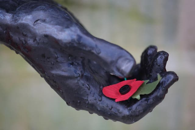 A poppy rests in the hand of a statue during the annual Armistice Day service at the National Memorial Arboretum in Staffordshire