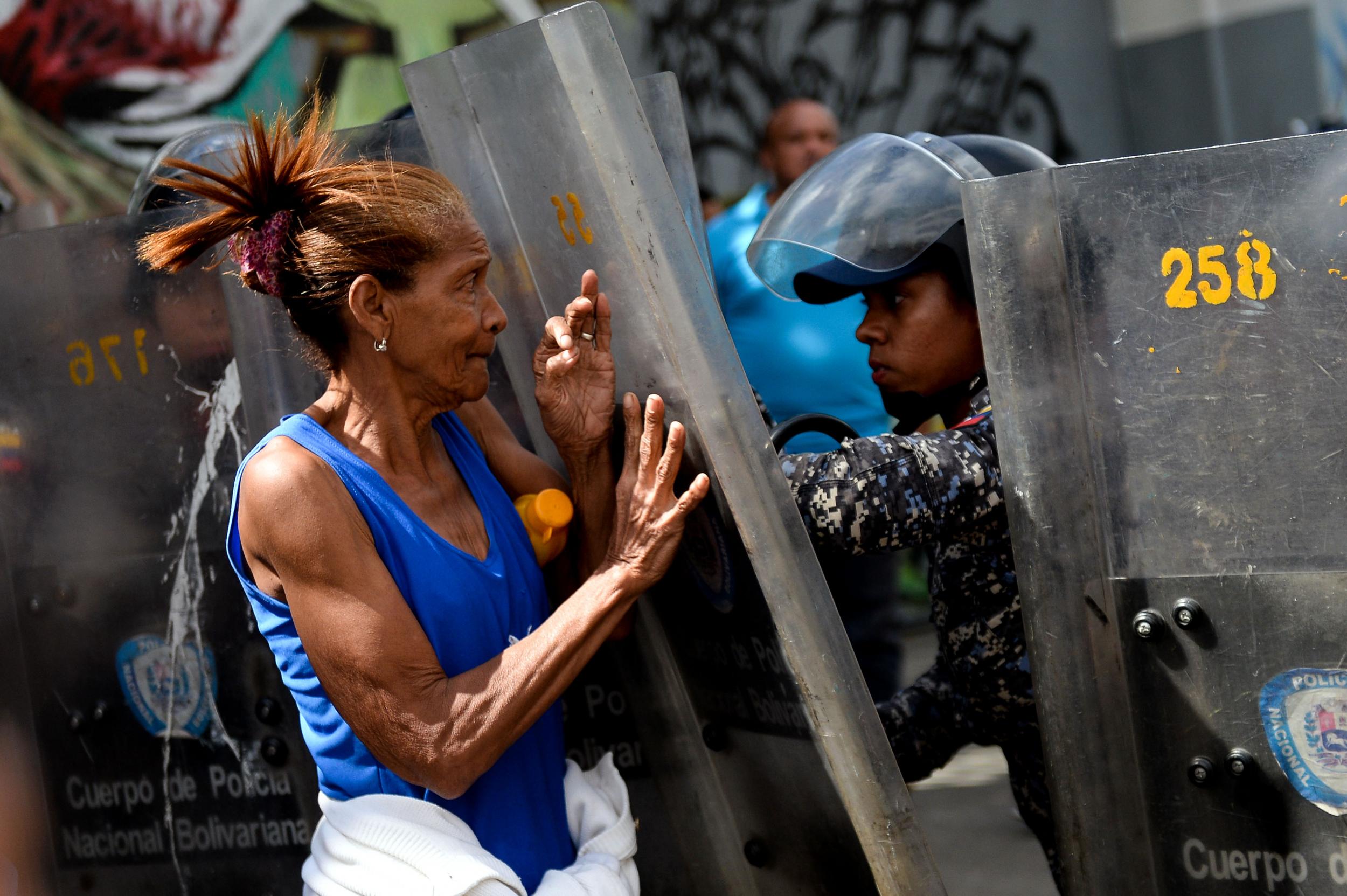 A Venezuelan woman confronts riot police during a protest against the shortage of food in Caracas on 28 December