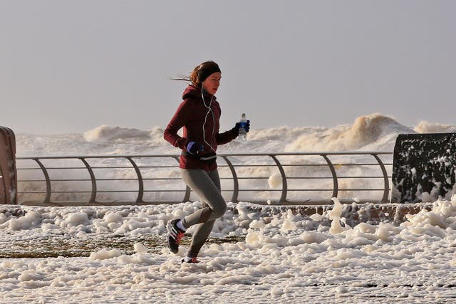 A woman jogs through sea foam in Blackpool as Storm Eleanor lashed the UK