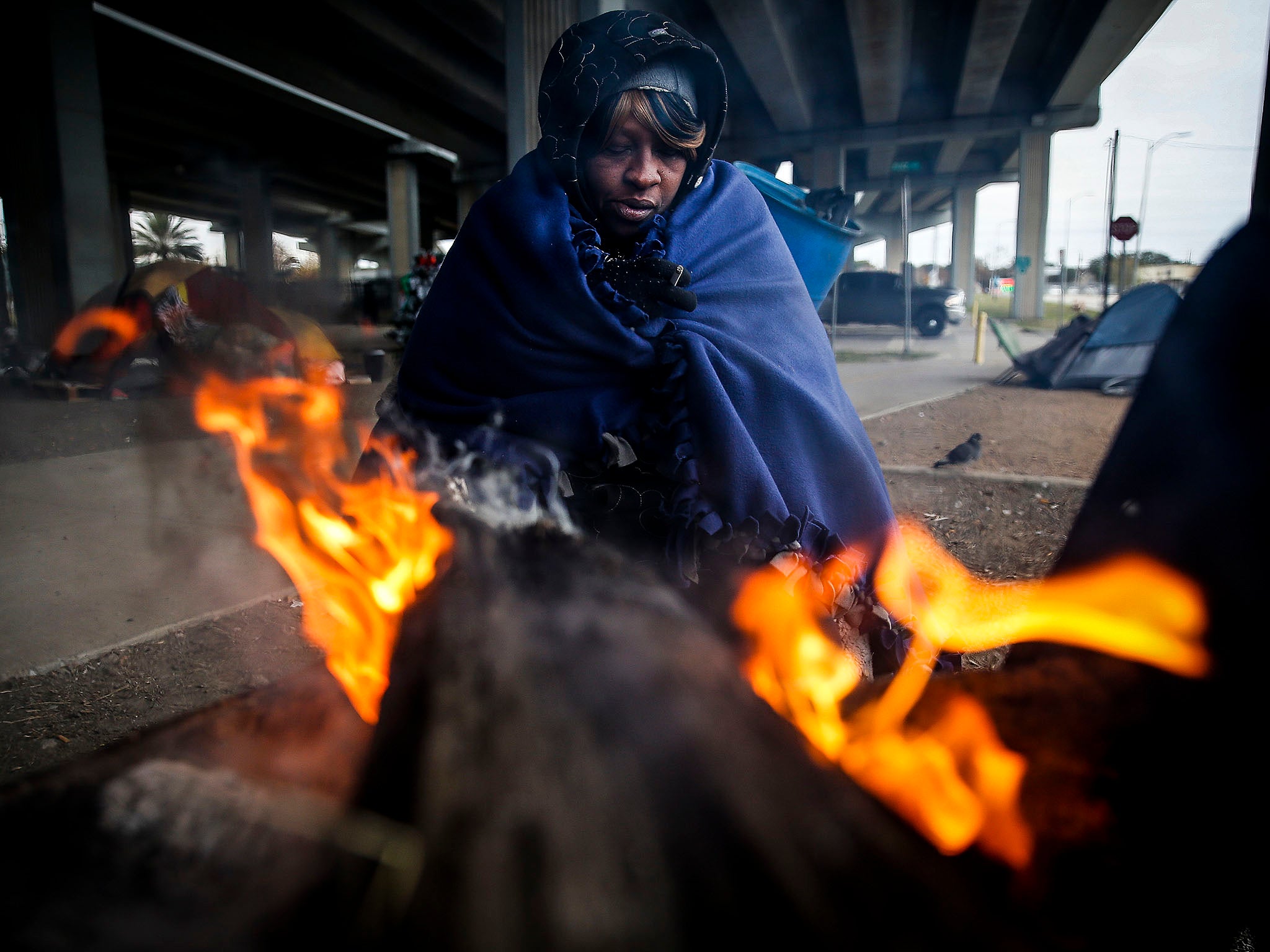 &#13;
Tony Sampson tries to warm up by a fire under the Eastex Freeway in Houston, Texas, as temperatures drop &#13;