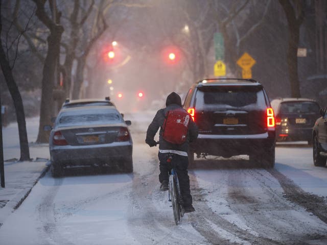 A man on a bicycle rides through the snow, January 4, 2018 in the Brooklyn borough of New York City