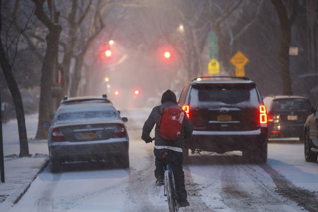 A man on a bicycle rides through the snow, January 4, 2018 in the Brooklyn borough of New York City