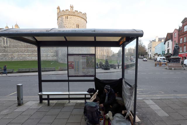 A homeless man with his possessions at a bus stop near Windsor Castle, Berkshire