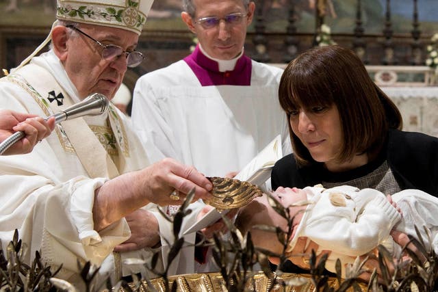 Pope Francis baptises a child during the ceremony at the Sistine Chapel