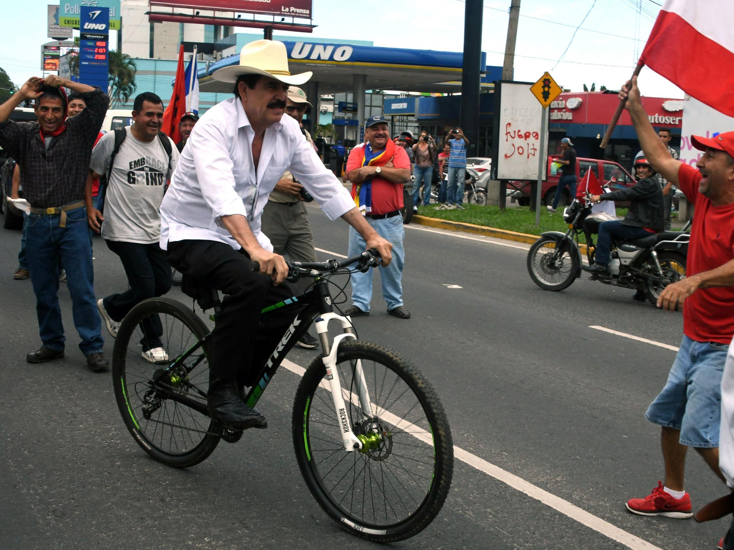 Former President Manuel Zelaya (centre) rides his bike to take part in the protest