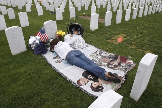 Jenn Budenz lies on a blanket with her two-month-old son, AJ, as they visit the grave of Major Andrew Budenz at Miramar National Cemetery on 22 May 2014 in San Diego