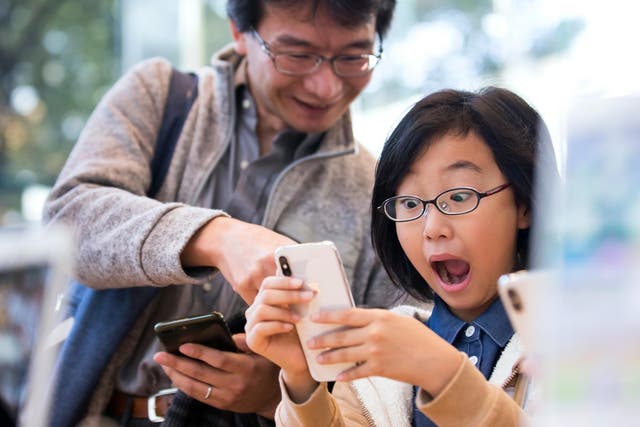 A girl reacts as she tries an iPhone X at the Apple Omotesando store on November 3, 2017 in Tokyo