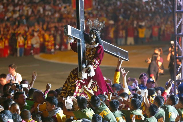 Roman Catholic devotees mount the image of the Black Nazarene on a hearse prior to a raucous procession to celebrate its feast day