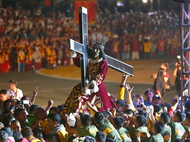 Roman Catholic devotees mount the image of the Black Nazarene on a hearse prior to a raucous procession to celebrate its feast day