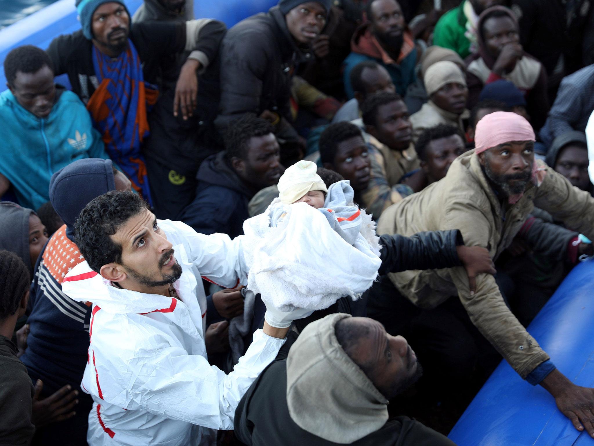 A refugee baby is carried as other refugees in a dingy are rescued by Libyan coast guards off the coast of Garabulli, east of Tripoli, Libya