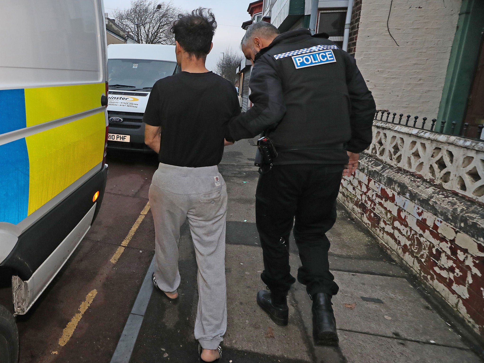 Police lead away a man after a raid at an address in Stockton, Teesside, as part of a crackdown on people trafficking and serious sexual offences