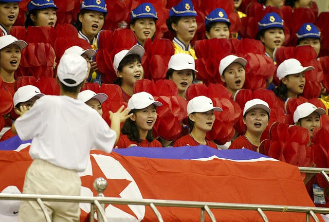 North Korean official cheerleaders sing prior to the start of the women’s weight lifting final at the 14th Asian Games in 2002