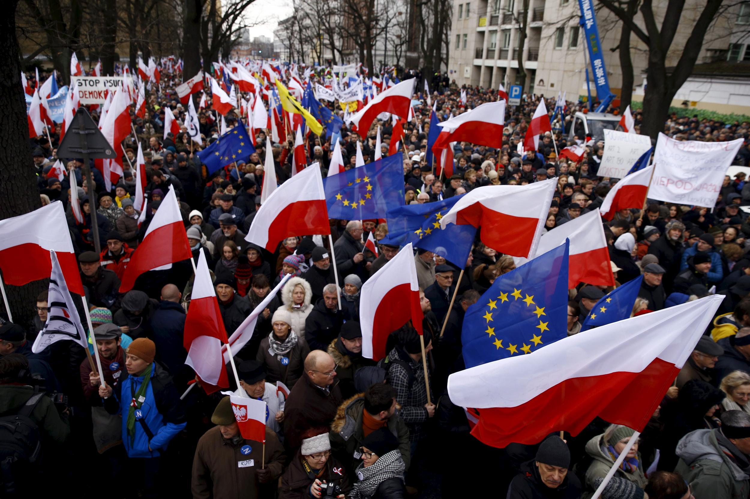 People hold EU and Polish national flags during an anti-government demonstration in front of the Constitutional Court in Warsaw