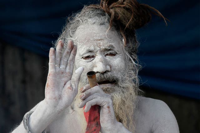 A sadhu, or a Hindu holy man, blesses a devotee as he smokes marijuana at a transit camp on the way to Gangasagar