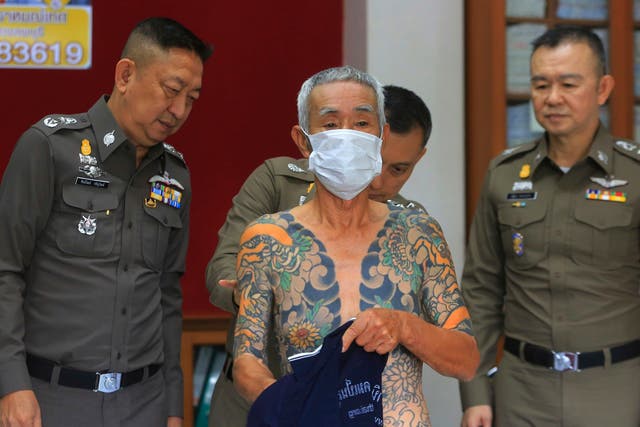 Japanese gang member Shigeharu Shirai displays his tattoos at a police station in central Thailand