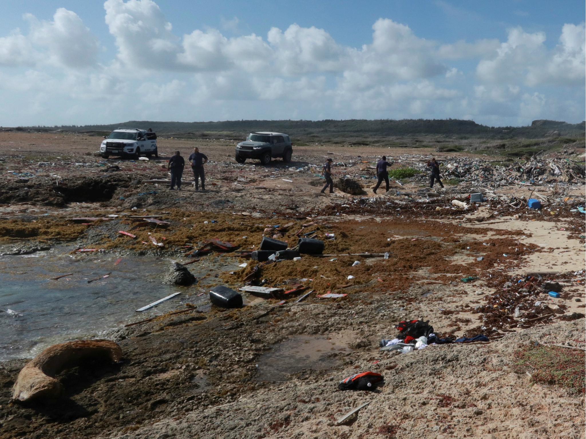 Police officers work next to the shore where bodies of four people were found, after their boat broke apart several miles before reaching Curacao 10 January 2018.