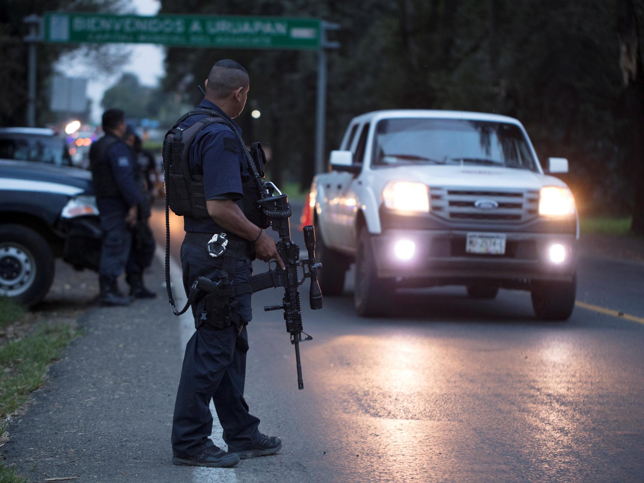 Police officers stand guard as they carry out inspections at a checkpoint in Michoacan