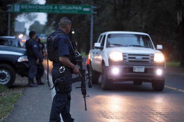 Police officers stand guard as they carry out inspections at a checkpoint in Michoacan