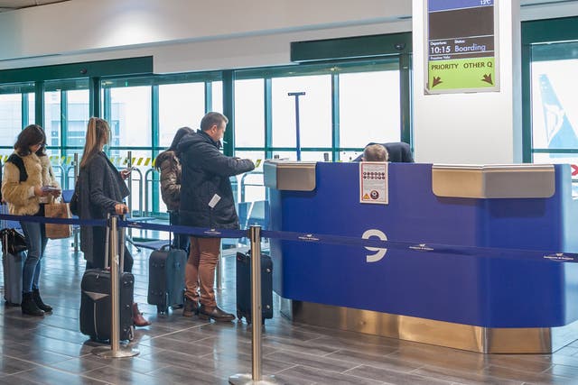 <p>Passengers at a Ryanair check-in counter</p>