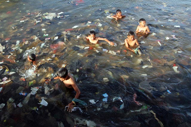 Plastic is polluting the world’s oceans: children swim in a sea full of garbage in North Jakarta, Indonesia