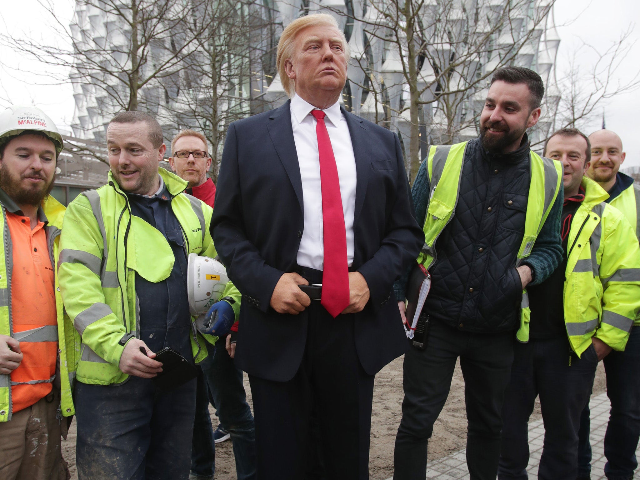 Workers look at a waxwork of Mr Trump after he confirmed he will not travel to the UK to open the new US Embassy