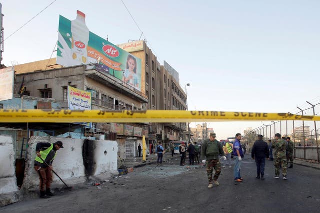Iraqi security forces inspect the site of the double bombing in Baghdad on Monday
