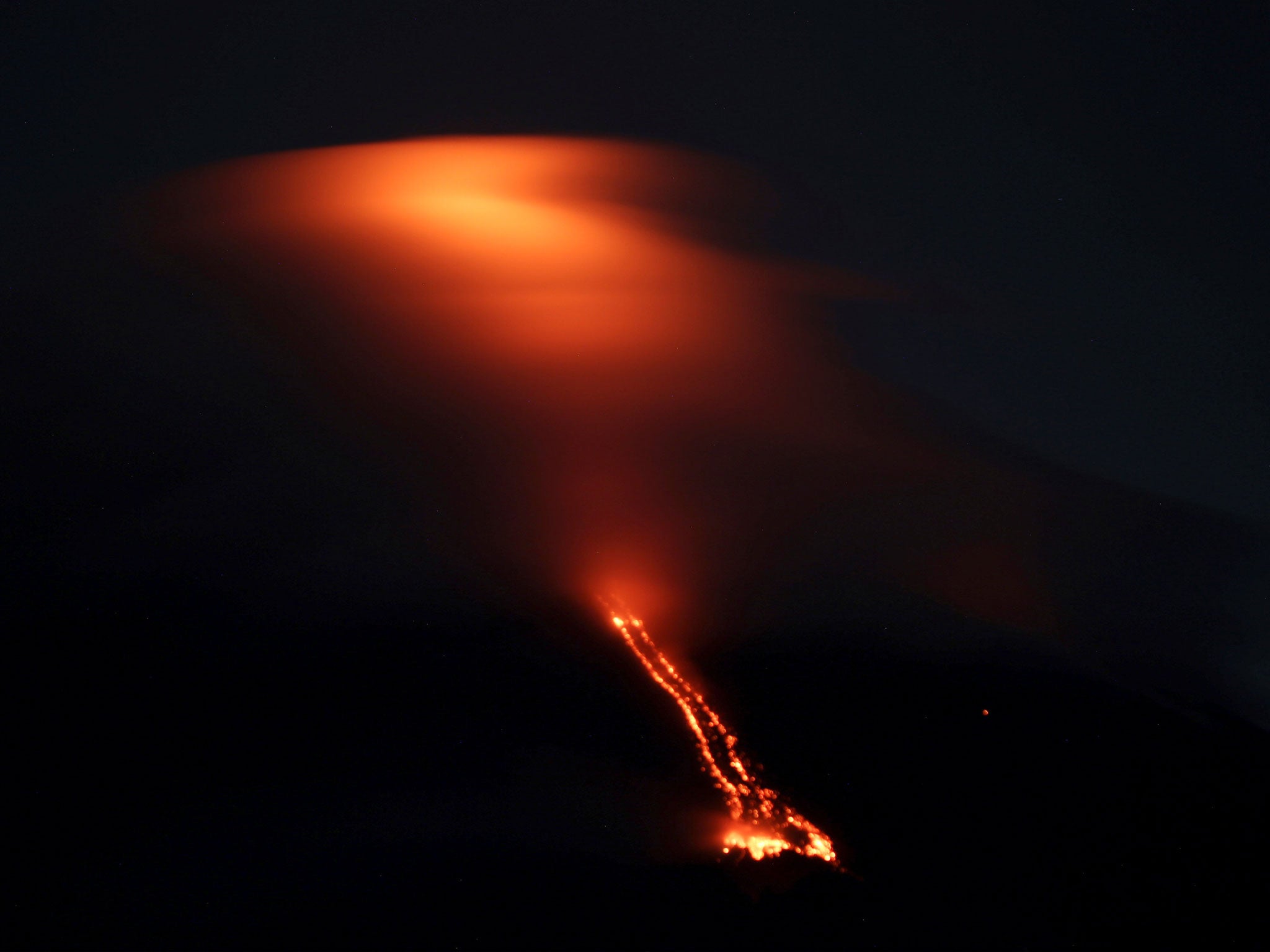 The reddish glow of lava drifting from Mayon volcano