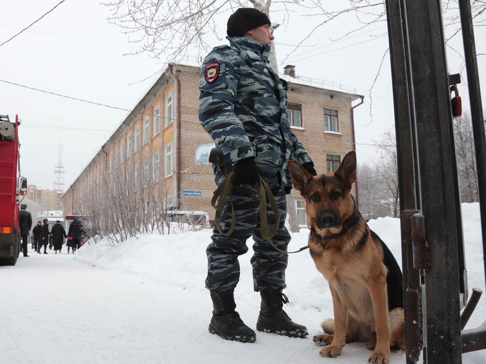 A policeman with a dog stands guard near the school after a knife fight broke out