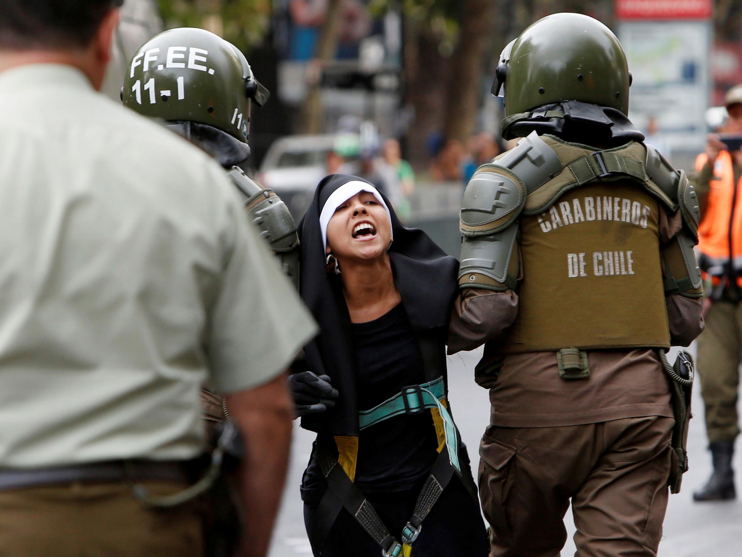 Police detain a protester dressed as a nun during the arrival of Pope Francis in Santiago