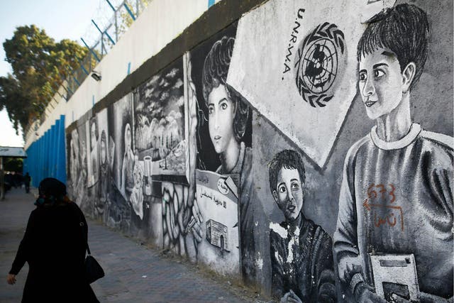 A Palestinian women walks past graffiti painted on the wall of the building of the UNRWA headquarters in Gaza City on 8 January 2018.
