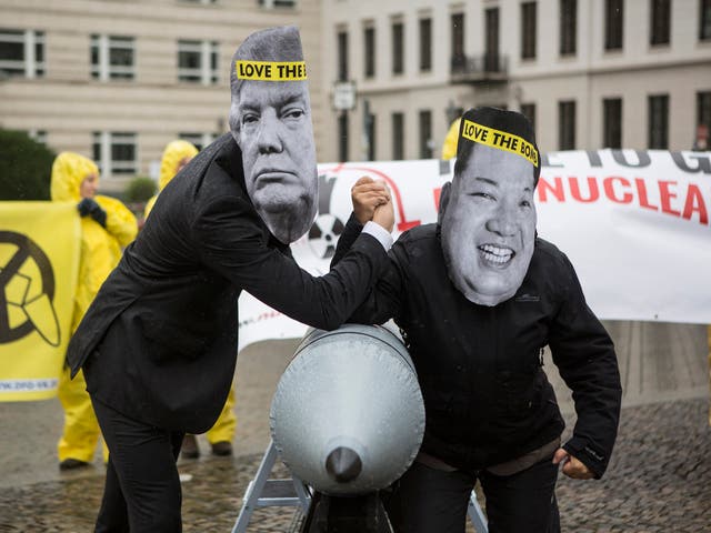 International campaign to abolish Nuclear Weapons activists wearing masks to look like US President Donald Trump and North Korean Kim Jong-Un pose next to a Styrofoam effigy of a nuclear bomb.