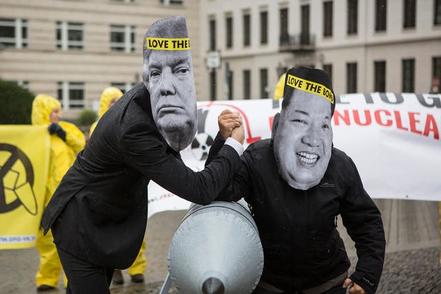 International campaign to abolish Nuclear Weapons activists wearing masks to look like US President Donald Trump and North Korean Kim Jong-Un pose next to a Styrofoam effigy of a nuclear bomb.