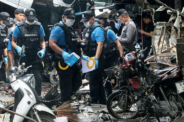 A Thai forensics unit scours the aftermath of a motorcycle bombing which killed three civilians and wounded others at a market in the restive southern Thai province of Yala