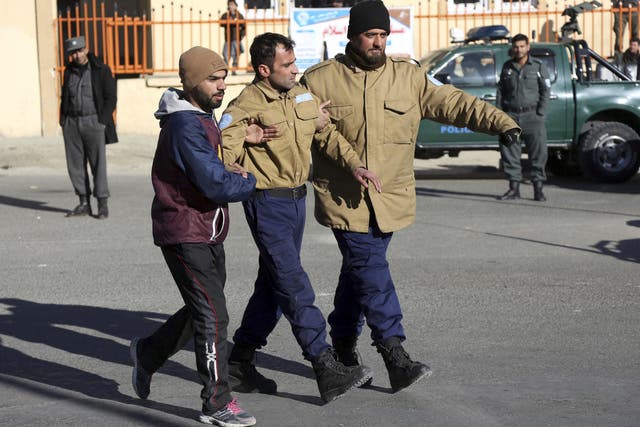 Afghan security personnel escort a man rescued from the Intercontinental Hotel after the attack in Kabul
