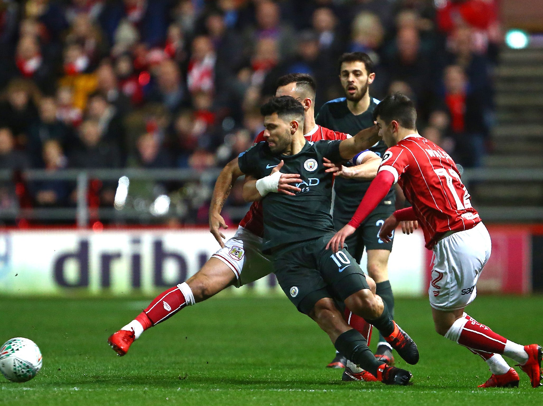 Sergio Aguero holds off the attentions of two defenders