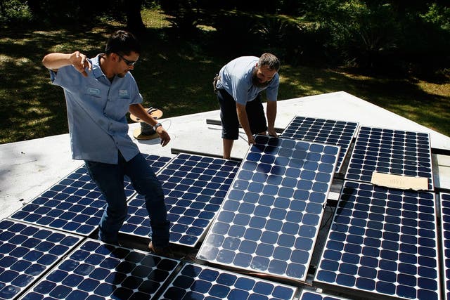 Workers install a solar panel system on the roof of a home in Gainesville, Florida.