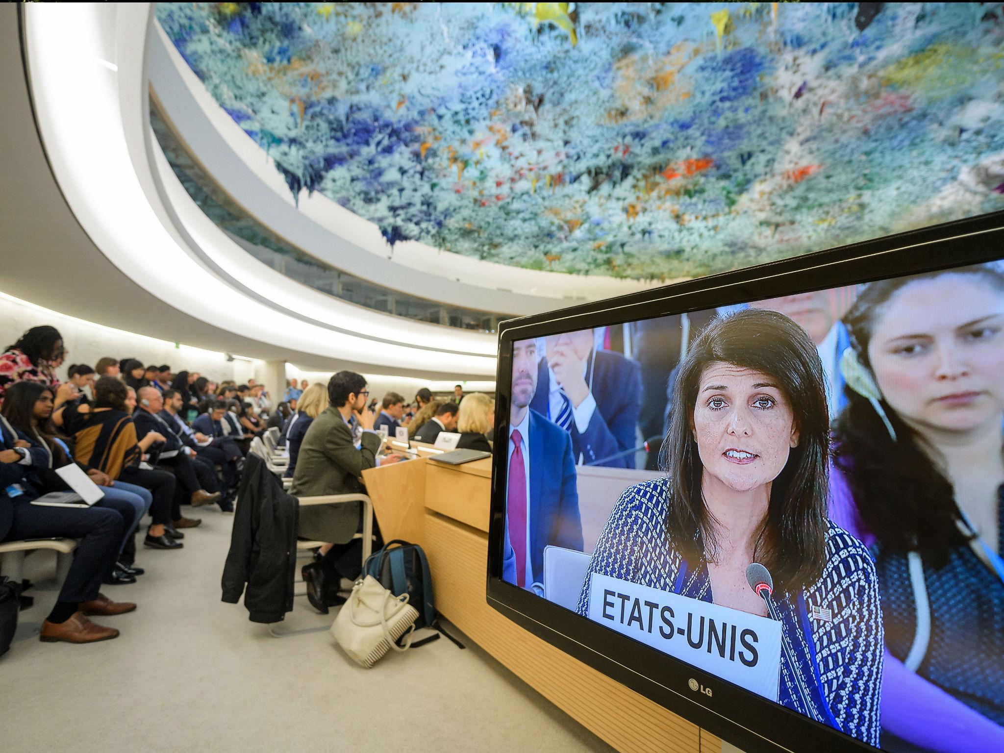 People sit next to a screen showing US Ambassador to the United Nations Nikki Haley addressing the United Nations Human Rights Council on 6 June 2017 in Geneva.