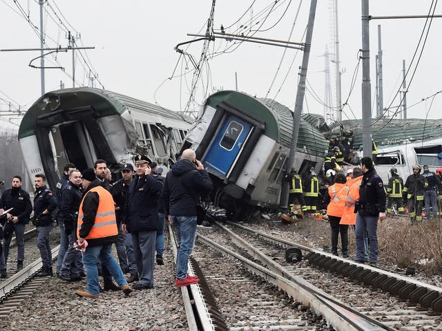 Rescue workers and police officers survey the derailed trains at Pioltello on the outskirts of Milan