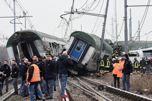 Rescue workers and police officers survey the derailed trains at Pioltello on the outskirts of Milan