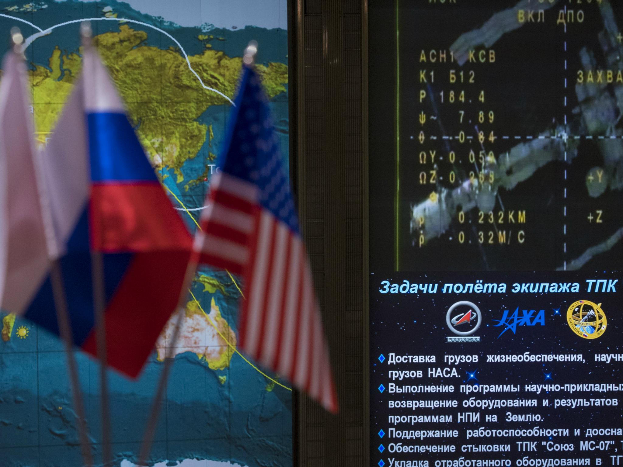 Icons for the International Space Station and Soyuz MS-07 spacecraft are seen on a tracking map along with live video are seen on screen in the Moscow Mission Control Center 19 December 2017