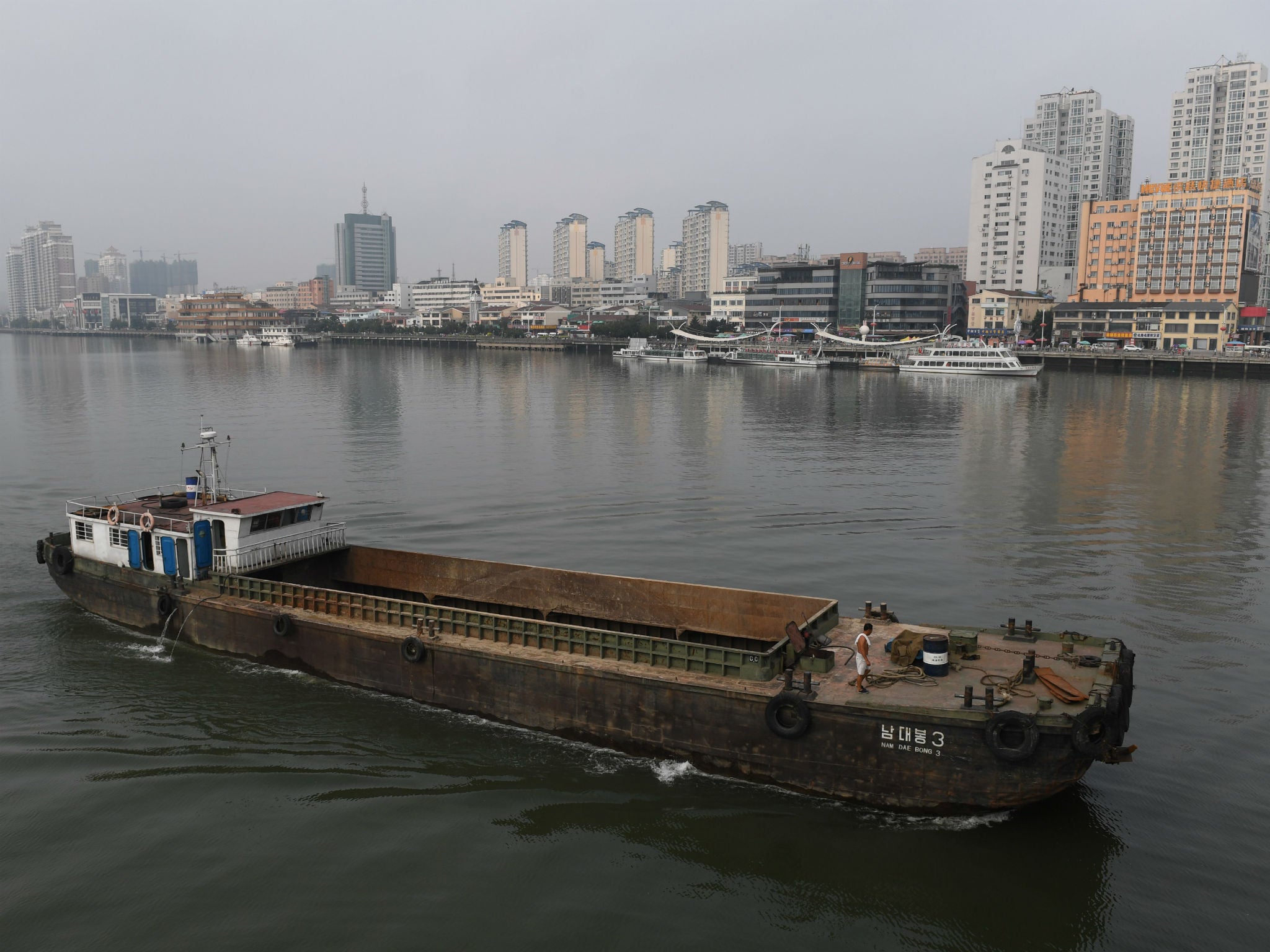 A North Korean ship passes in front of the waterfront of the Chinese border city of Dandong