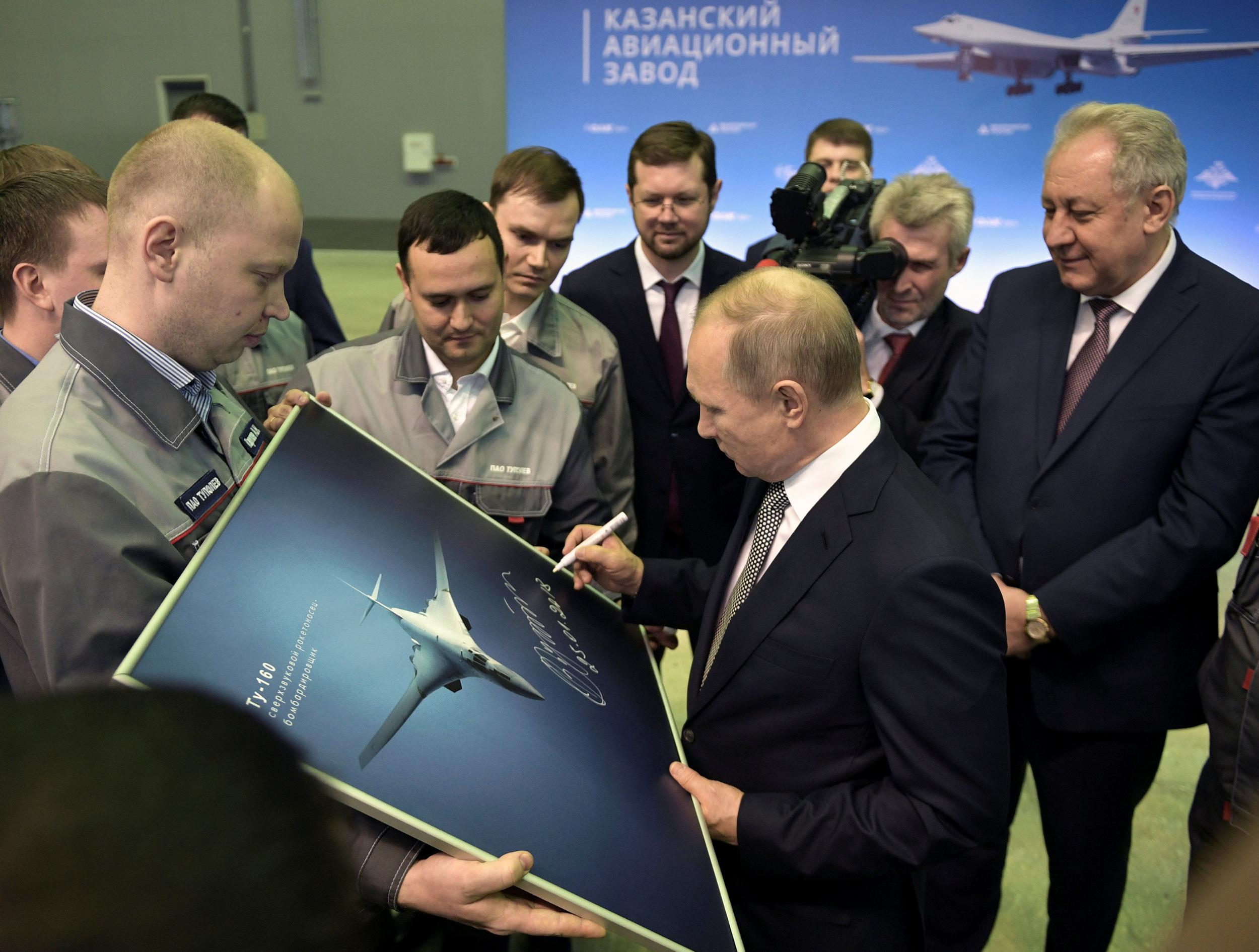 Vladimir Putin signs a picture of a TU-160M nuclear bomber