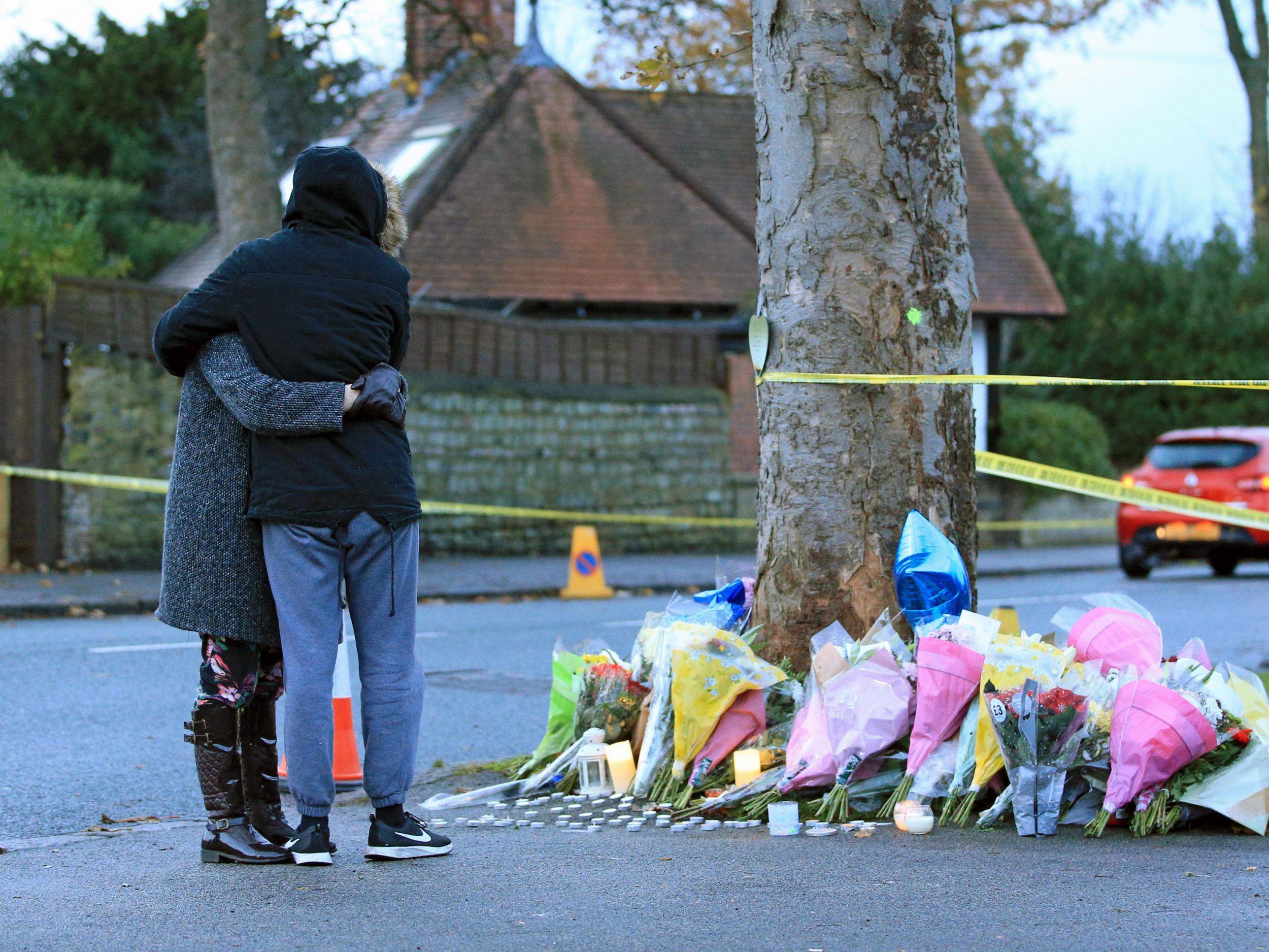 People hug as they look at floral tributes near the scene of a car crash in Stonegate Road, Leeds, that claimed the lives of five people, including three children