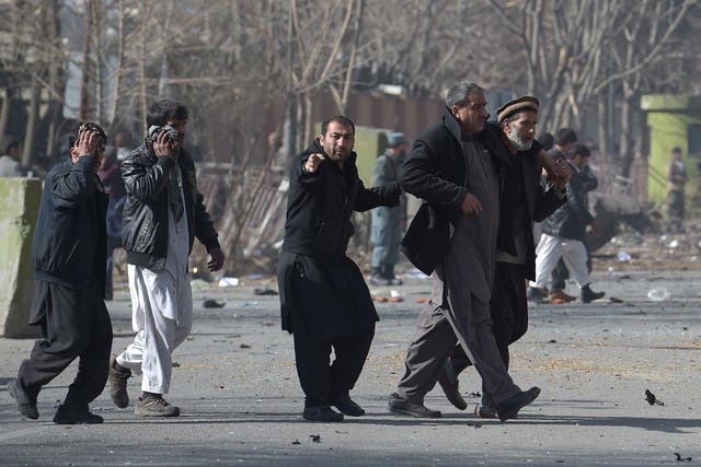 Afghan volunteers help an injured men at the scene of a car bomb exploded in front of the old Ministry of Interior building in Kabul on 27 January 2018
